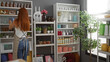 © Krakenimages.com - Redheaded woman decorating stylish home decor store with attractive indoor decorations including vases, plants, and art, creating an inviting interior setting.