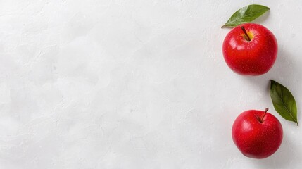 Wall Mural - Two ripe red apples with green leaves on a white background.