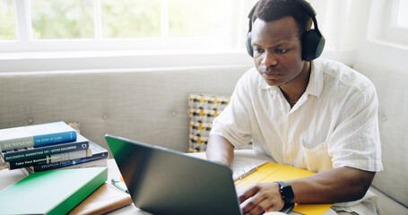 Poster - Black man, laptop and headphones with typing in home with studying, assessment or listening to music with scholarship. Person, student and computer with notes, education or elearning for college exam