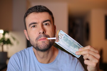 Man burning one hundred dollars to light his cigarette