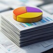 © Espresso - Colorful pie chart on a stack of business reports and data sheets, illustrating financial analysis and marketing strategies.