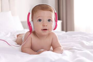 Canvas Print - Cute little baby with headphones on bed at home