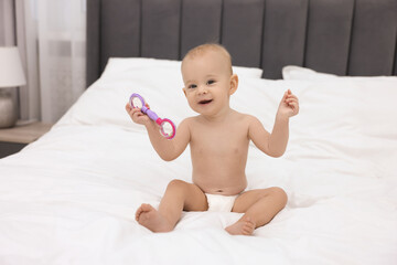 Wall Mural - Cute little baby with rattle on bed indoors