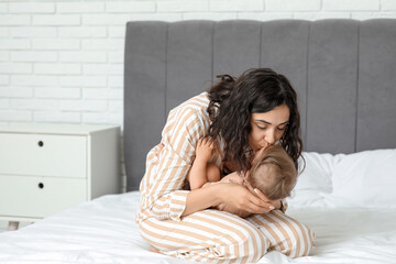 Poster - Happy mother kissing her little baby on bed at home