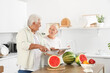 © Pixel-Shot - Mature couple cutting watermelon in kitchen