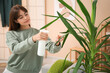 © Pixel-Shot - Young female gardener spraying houseplant leaves at home