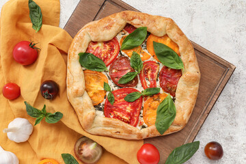 Wall Mural - Composition with tasty tomato galette, basil and garlic on light background