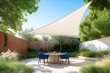 © Viktor - Modern house patio in summer. Dining table, chairs under shade sail. Outdoor living space in contemporary garden. Light beige shade sail covers circular patio area with wooden table, blue chairs.