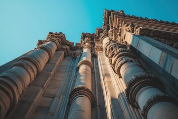 Poster - Low-angle view of ornate columns on a building against a clear blue sky.