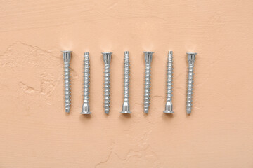 Wall Mural - Row of screws on beige background