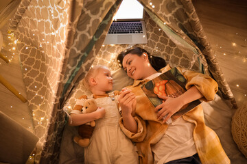 Poster - Cute little girl with her mother lying in play tent at night, top view