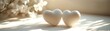 © Itsaree  - Two white hearts surrounded by soft light and gentle shadows on a pale background, minimalist and harmonious design