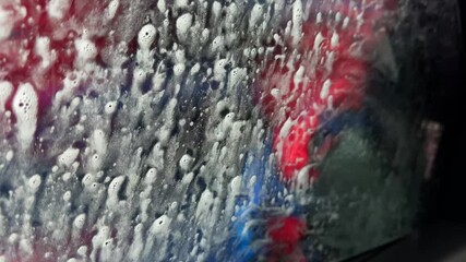 Wall Mural - A car window is covered in water spots and streaks. The car is being washed.