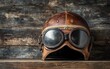 © Itsaree  - Antique leather aviator helmet and goggles placed on a rustic wooden surface, nostalgic and adventurous vibe, perfect for retrothemed decor, vivid details