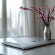 © Annda - silver laptop resting on a table, the blurred image of a vase with bright blossoms adding a touch of softness
