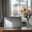 © Annda - silver laptop resting on a table, the blurred image of a vase with bright blossoms adding a touch of softness