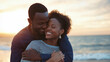 © Helga - A loving young couple hugging and kissing on the beach.