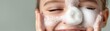 © Phisan - Close-up of a smiling young girl using a facial exfoliator in her skincare routine