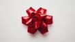 © Thirawat - A bright red gift bow with a glossy finish and textured ribbon loop rests against a smooth white background.