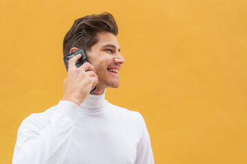 Wall Mural - Young caucasian man at outdoors keeping a conversation with the mobile phone with someone