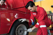 © amorn - Male mechanic using pneumatic wrench changing tyre of car at auto repair shop. Mechanic checking, repair and maintenance wheel of car. Auto car repair service and maintenance concept