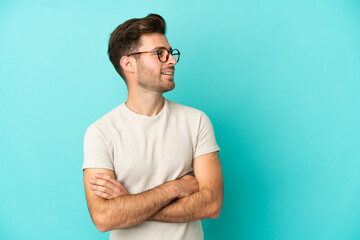 Wall Mural - Young caucasian handsome man isolated on blue background happy and smiling