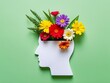 © Tharusha - Human head silhouette with open mind and colorful flowers inside on pastel green background, flat lay concept for mental health or brain activity idea.