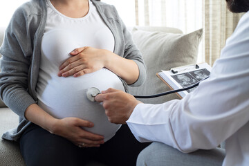 Doctor with stethoscope examining pregnant woman at home. Concept caring for pregnant woman