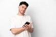 © luismolinero - Young caucasian man isolated on white background using mobile phone and pointing back