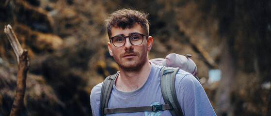 A man with glasses, a purple shirt, and a backpack, outdoor