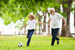 © famveldman - Grandfather and kids play football in summer park