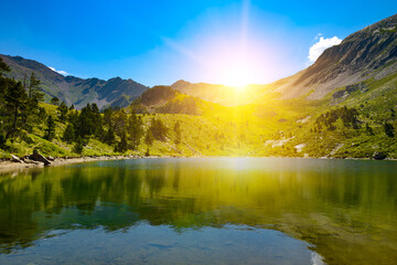 Wall Mural - Bright sunrise over a picturesque small lake high in mountains against sky.