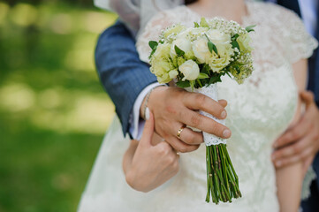 Wall Mural - Romantic Wedding Moment Featuring Bride and Groom Embracing with a Beautiful Floral Bouquet