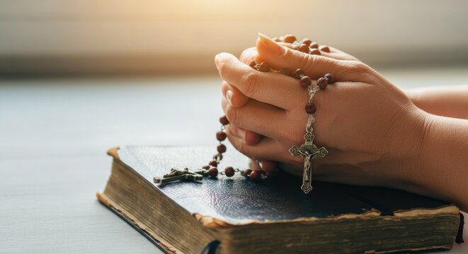 Hands holding rosary over book, suggesting prayer or meditation