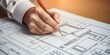 © Redhill - architect working on project. An architect's hand meticulously draws a building plan with a pen, capturing the essence of architectural planning and design, emphasizing precision and creativity