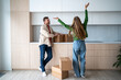 © DimaBerlin - Joyous married couple embarks on new chapter as move into new home. Pleased husband and overjoyed wife share triumphant look moving to new light apartment. Happy woman joy jumping feeling housewarming
