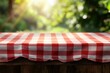 © Muhammad - Red checkered tablecloth on wooden table, sunny garden background.