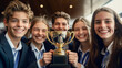 © Atchariya63 - Group of happy young students celebrating their victory with a trophy in a joyful atmosphere.