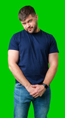 Man standing with a thoughtful expression in a casual outfit against a green background