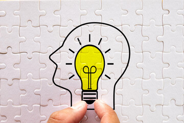 Human Head with light bulb icon on white puzzle symbolizing creativity, innovation, and ideas for educational visuals, motivational campaigns, and business strategy.