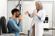 © Maria Vitkovska - Senior female doctor performing eye exam on male patient using phoropter in clinic