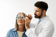 © Maria Vitkovska - Optometrist examining senior woman's vision with phoropter during eye exam