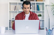 © nenetus - Smart entrepreneur working with laptop while listening music with headphone in a modern startup