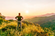 © Yaroslav - rejoicing man with beautiful scenic mountain sunset landscape on background. happy man watching amazing evening sunset