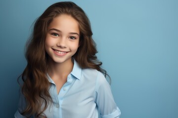 Wall Mural - soft features long hair, smiles gently woman while wearing blue shirt against simple plain background. Her relaxed posture calm expression convey sense of ease natural beauty.