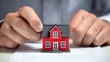 © TA Design - A person is placing a small red house on a document, suggesting a focus on real estate or property transactions.