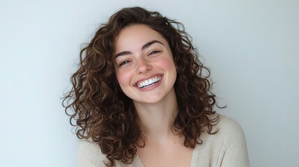 Wall Mural - Young Woman with Curly Hair Smiling Joyfully Against a Neutral Background