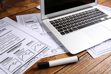 Wall Mural - developing ui design. sketches of website wireframes, laptop and felt pen on wooden table, closeup