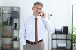 © New Africa - Happy businessman talking on smartphone in office