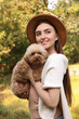 © New Africa - Smiling woman with cute dog in autumn park